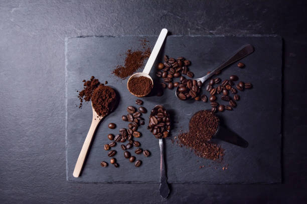istock Top down view of multiple spoons filled with roasted coffee beans or ground coffee. 1290603945