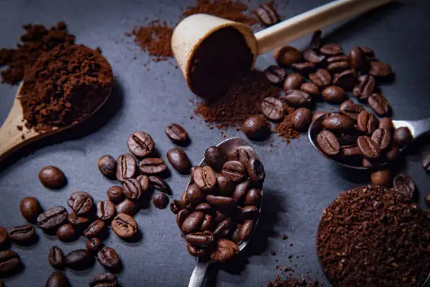 Photo of Different spoons filled with roasted coffee beans or with grinded coffee.