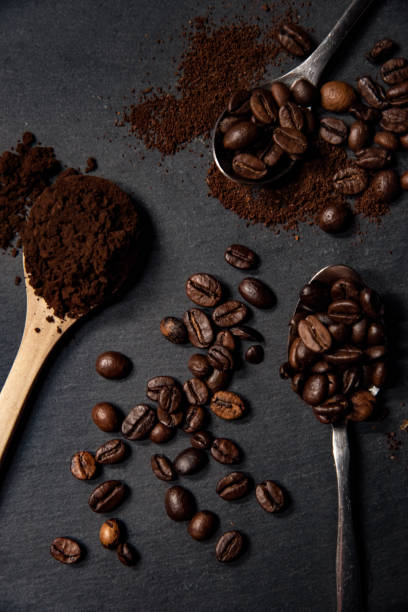 istock Spoons with roasted coffee beans and grinded coffee on a slate stone platter. 1290604198