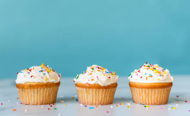 istock Cupcakes with sprinkles on white table with blue background. 1290605147