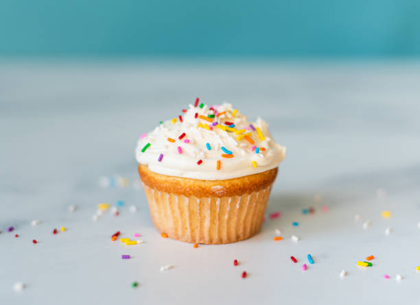 istock Vanilla frosted cupcake with sprinkles on a white surface. 1290605157