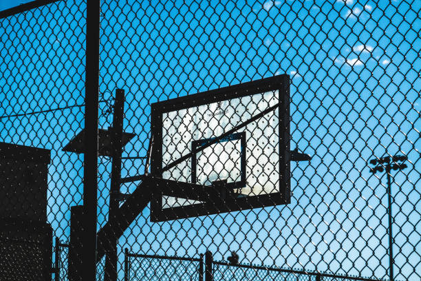Basketball backboard and hoop photographed off court and behind a fence