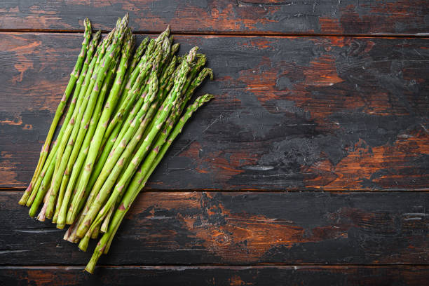 istock Raw organic asparagus on dark wooden old background, top view with space for text. 1290613954
