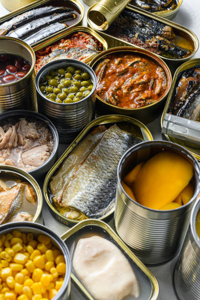 istock Tin cans for processed  food  cans conserve Saury, mackerel, sprats, sardines, pilchard, squid, tuna pinapple, corn, peas, mango ,  beans,   over white textured background close up side view 1290615958