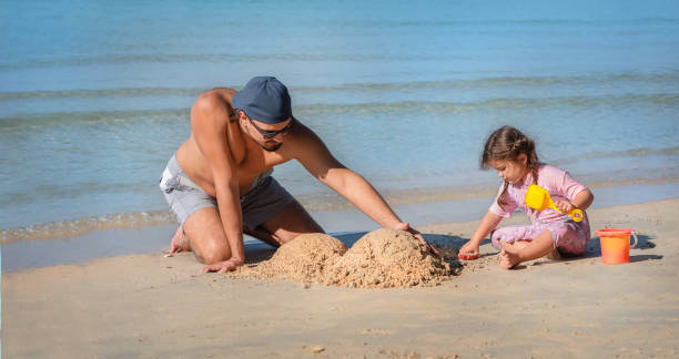istock dad and daughter are building the sand castle 1290616628