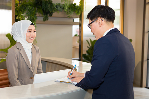 Young female Muslim receptionists are introducing hotel stays to travelers.