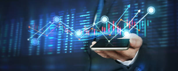 istock Hand holding smartphone device and touching screen. businessman trader looking on with graphs analysis candle 1290621656