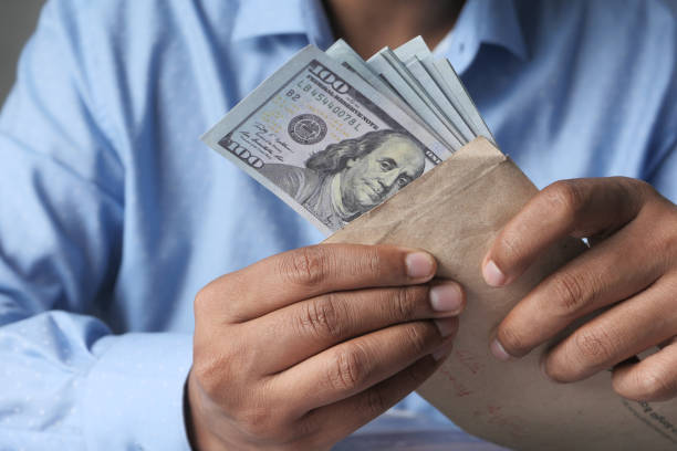 istock person hand putting cash in a envelope. 1290622800