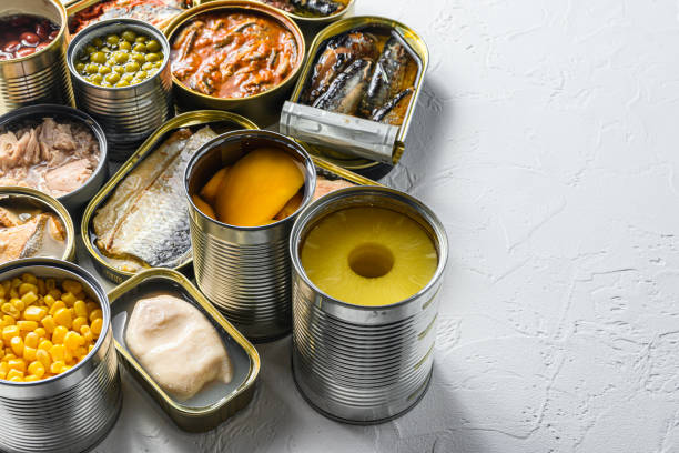istock Tin cans for processed  food  cans conserve Saury, mackerel, sprats, sardines, pilchard, squid, tuna pinapple, corn, peas, mango ,  beans,   over white textured background close up side view space for text 1290622849