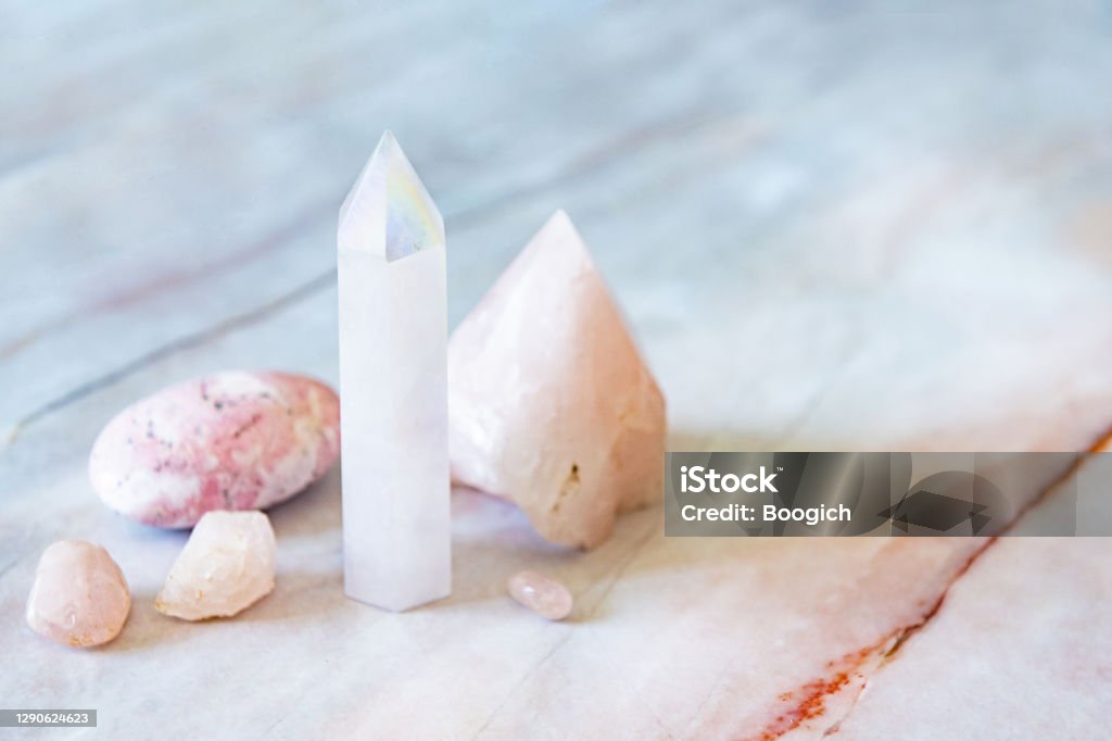Rose and Angle Aura Quartz Crystals with Rhodonite Palm Stone This is a photo of a variety of crystals including an angel aura quartz tower, rose quartz, and a rhodonite palm stone. Crystal Stock Photo