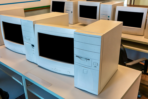 old CRT computer monitors and towers in classroom or office.