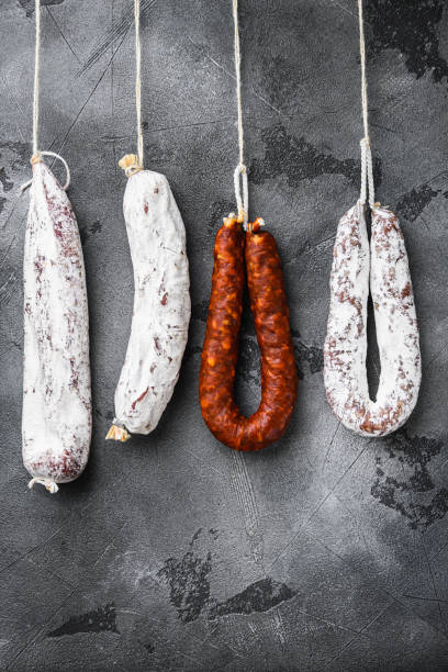istock Spanish dry salami from a rack at market on grey background 1290632934