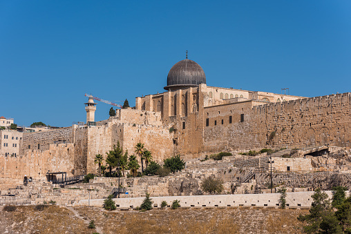 Siliver dome of Al-Aqsa Mosque, built on top of the Temple Mount, known as Haram esh-Sharif in Islam and wall of old city of Jerusalem, Israel. View from Mount of Olives.