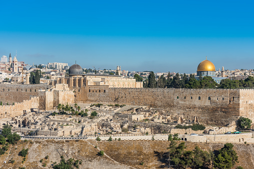 Dome of Al-Aqsa Mosque and golden dome of the Rock, built on top of the Temple Mount, known as Haram esh-Sharif in Islam and wall of old city of Jerusalem, Israel. View from Mount of Olives.