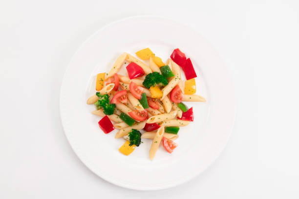 Top view of a delicious looking plate with freshly cooked pasta and vegetables on a light background. Healthy food and pasta concept.