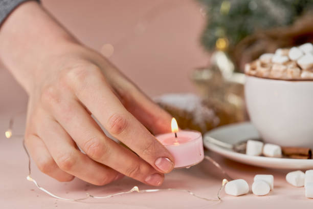 istock A hand puts a lighted candle on the table next to a mug of coffee and marshmallows. Preparation for a romantic evening 1290640107