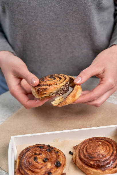 istock Hands tear off a piece of poppy seed roll. Chopping buns over the table 1290640152