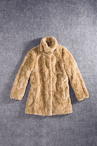 Fashionable  fur coat on gray background