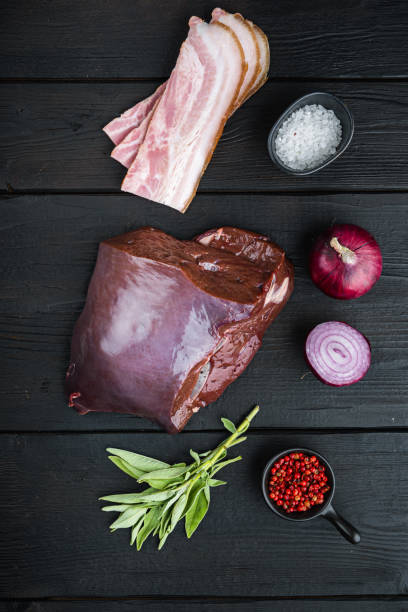 istock Beef liver with bacon and onion on black wooden background, top view 1290642017