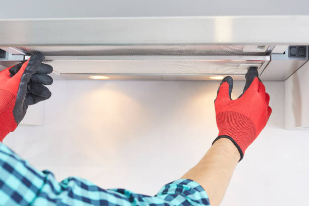 trabajador instalar filtro en la campana de la gama de la casa en la cocina. handyman quitando el filtro de una campana de escape. reparación de la campana de cocina. - range hood fotografías e imágenes de stock