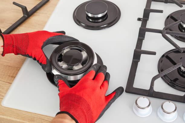 istock Worker install burner on gas hob in kitchen interior. Repairs of gas control panel. 1290646995