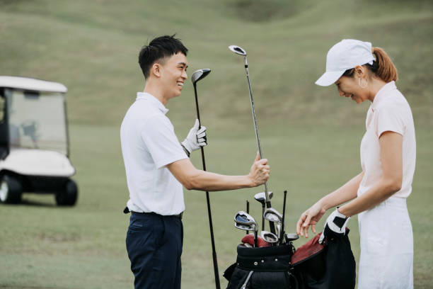 asiatische chinesische paar golfer auspacken golfausrüstung auf golfplatz - golf golf course putting green hole stock-fotos und bilder