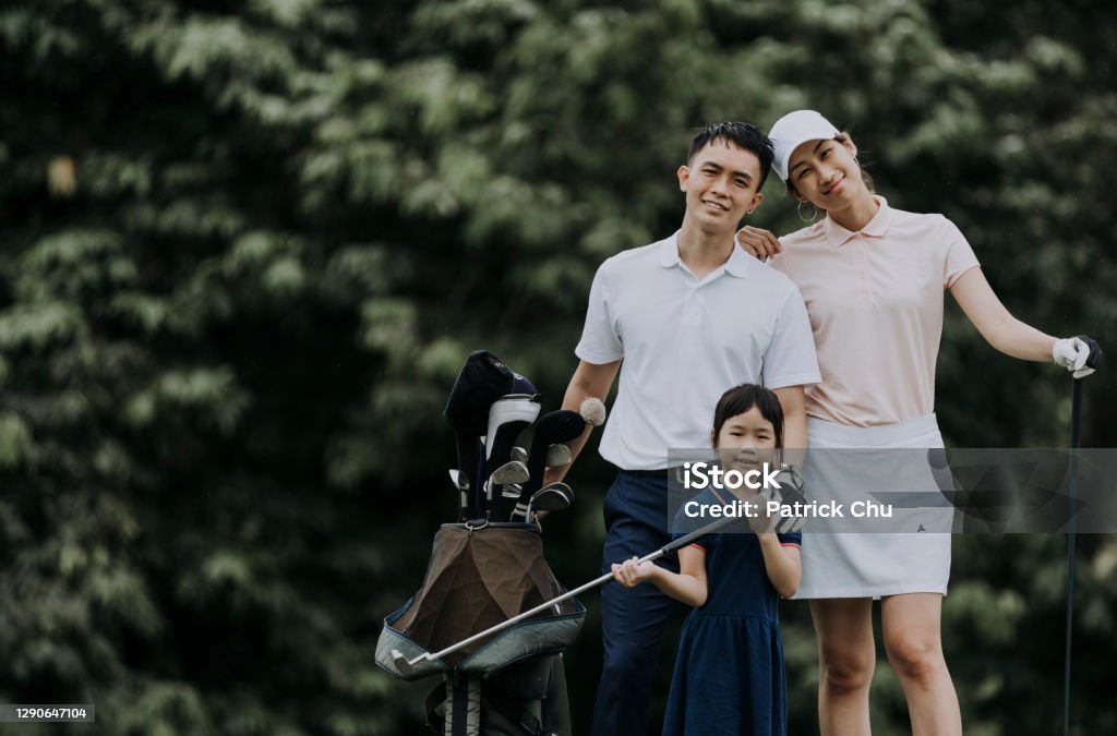 happy asian chinese couple golfer with their daughter smiling and looking at the camera at golf course golf Family Stock Photo