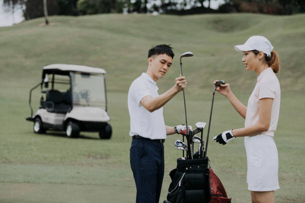 asiatische chinesische paar golfer auspacken golfausrüstung auf golfplatz - golf golf course putting green hole stock-fotos und bilder