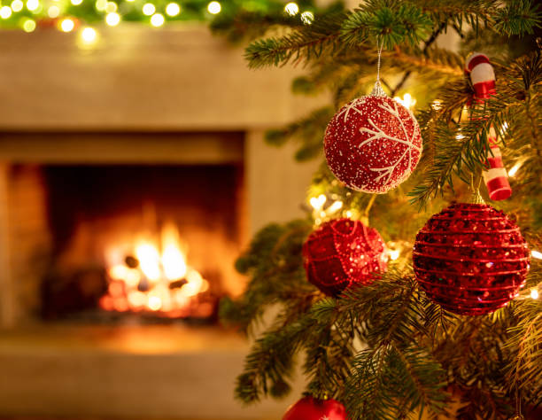 istock Christmas tree close up on blurred burning fireplace background 1290648270