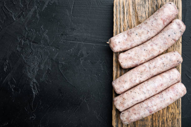 istock Raw chicken sausages, flat lay with space for text, on black background 1290649808