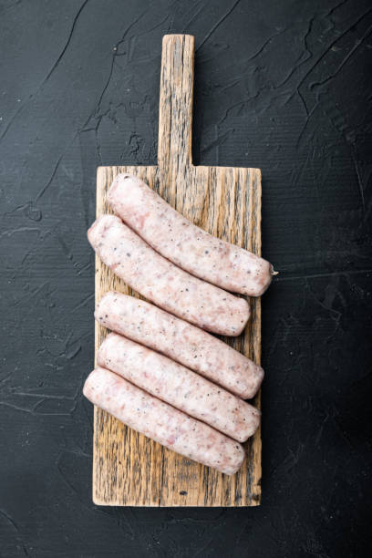 istock Raw chicken sausages, flat lay, on black background 1290651175