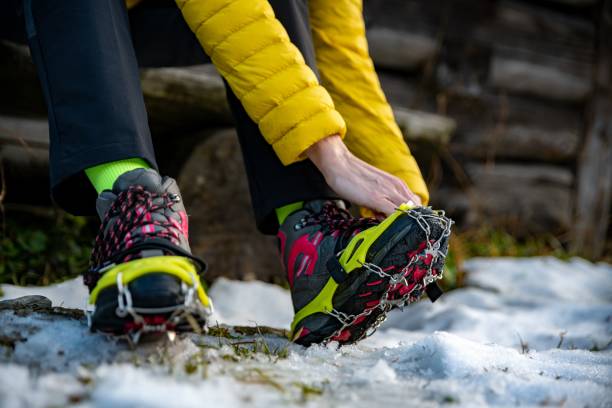 女性登山家は冬に山に登る前にブーツのためにクランポンを着用します。 - tatra national park ストックフォトと画像
