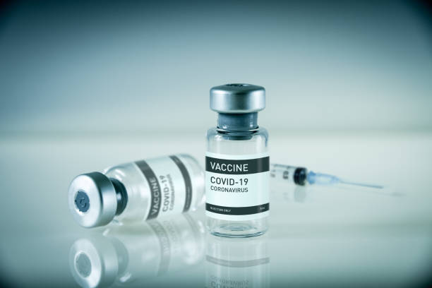 бутылка вакцины covid-19 и шприц на синем фоне - covid vaccine стоковые фото и изображения