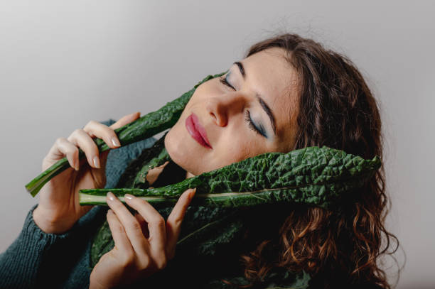istock Woman smiling face between green leafy vegetable. 1290655721
