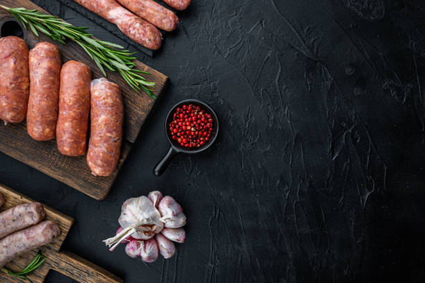 istock Assorted fresh raw pork, beef and chicken sausages, top view with space for text, on black background 1290655734
