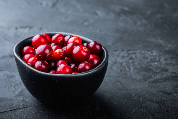 istock Ripe cranberry in black bowl with space for text, on black background 1290657510
