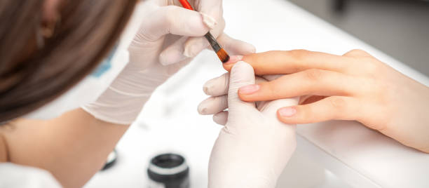 istock Manicurist covering nails with transparent polish 1290657957