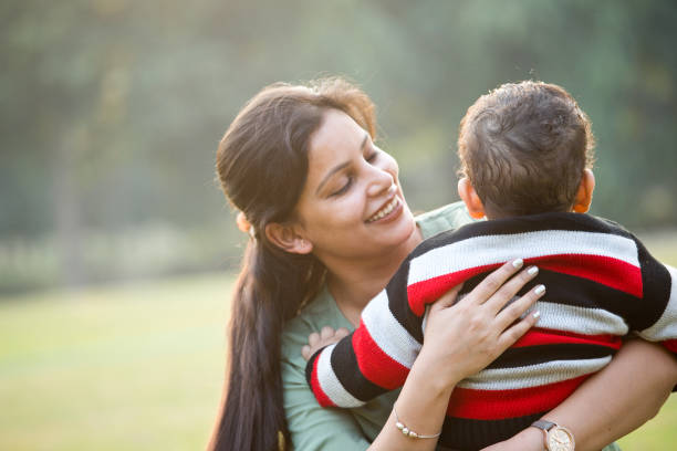 istock Mother carrying baby son at park 1290658738