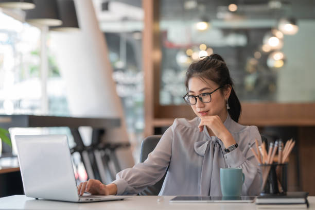 istock Young beautiful woman using her laptop while sitting in chair at her working place. 1290662301