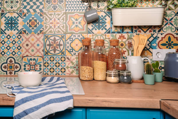 istock Cozy home style modern kitchen with colorful patchwork tiles, spice jars, glass jars with cereals and other kitchen accessories 1290663262