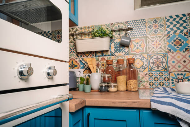 istock Cozy home style modern kitchen with colorful patchwork tiles, spice jars, glass jars with cereals and other kitchen accessories 1290663359