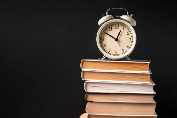 istock The alarm clock stands on a stack of books on a black background. Training concept and preparation for work 1290663887