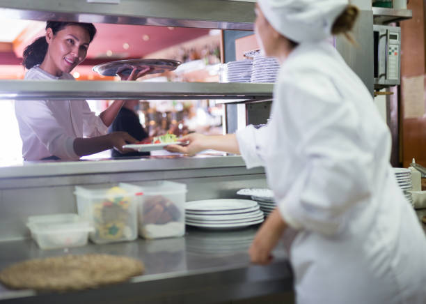 istock Smiling waitress taking cooked meals in restaurant kitchen 1290671258