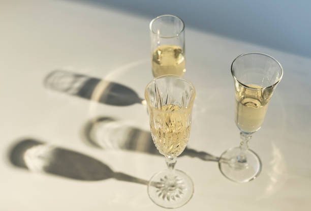 flautas de champán proyectando sombra sobre una mesa blanca - wine red wine pouring wineglass fotografías e imágenes de stock