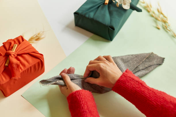istock Girl wrapping a gift on brown fabric 1290676974