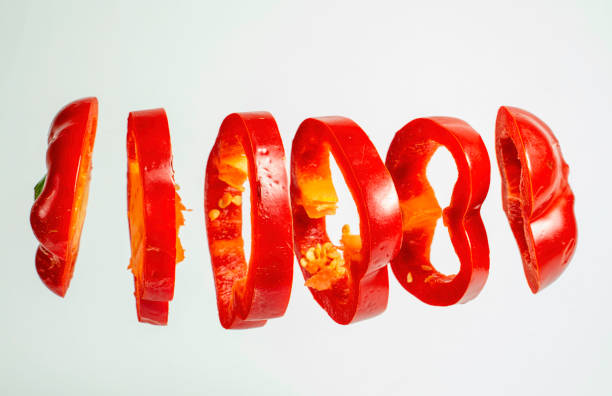 istock Red bell pepper slices floating isolated on white background 1290678646