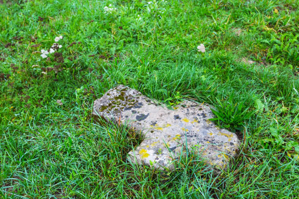 Antique rusty decorative iron cross on a cemetery ground. Monochrome image
