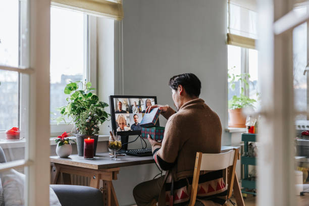 istock Japanese man opens Christmas present received from his co-workers during virtual Christmas party 1290680029