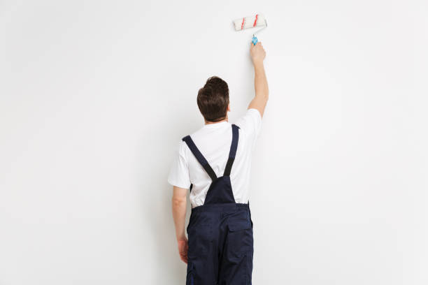istock Back view of Young builder painting wall with paint roll 1290681313