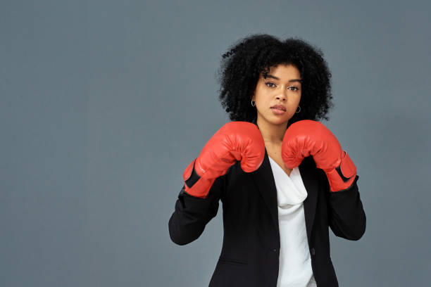 Your intimidation tactics won't work on me Shot of young businesswoman wearing red boxing gloves against a grey studio background business battle stock pictures, royalty-free photos & images